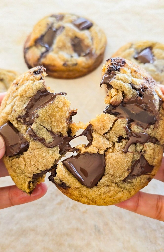 Chocolate chip cookie with melting chocolate chips being pulled apart.