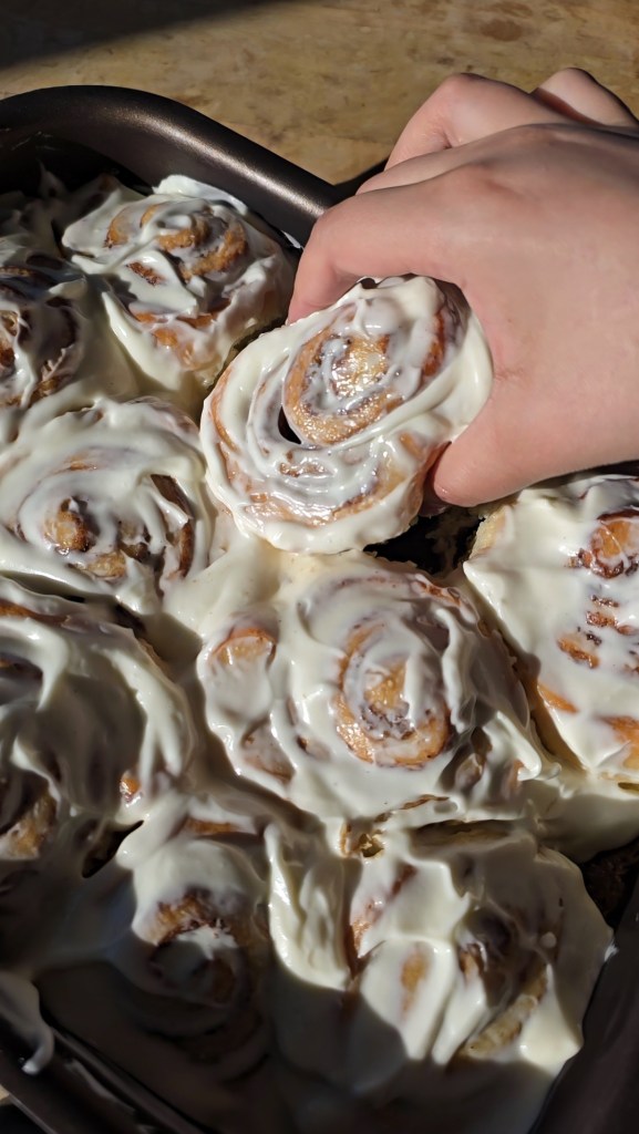 Taking a cinnamon roll out of the pan