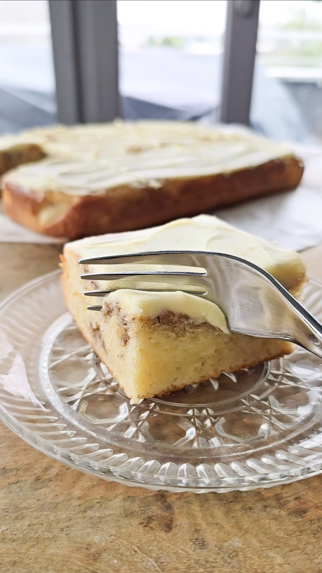 Slice of vanilla cinnamon cake with white chocolate frosting taking a bite